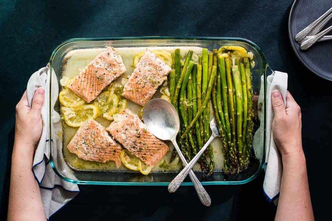 A glass baking dish with asparagus and lemons.