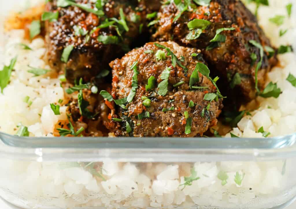 Meatballs and cauliflower rice in a clear container.