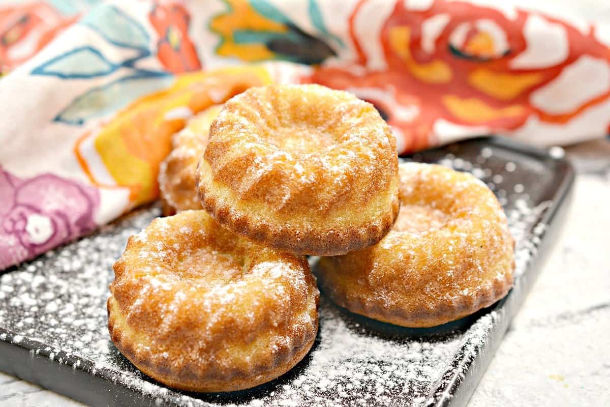 Three pastries on a plate with powdered sugar.