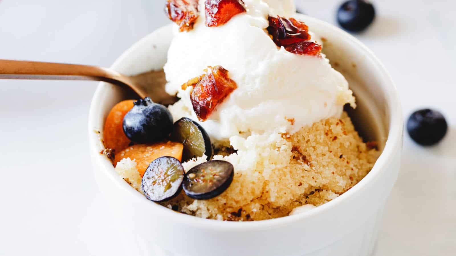 A classic dessert - a white bowl filled with ice cream and blueberries.