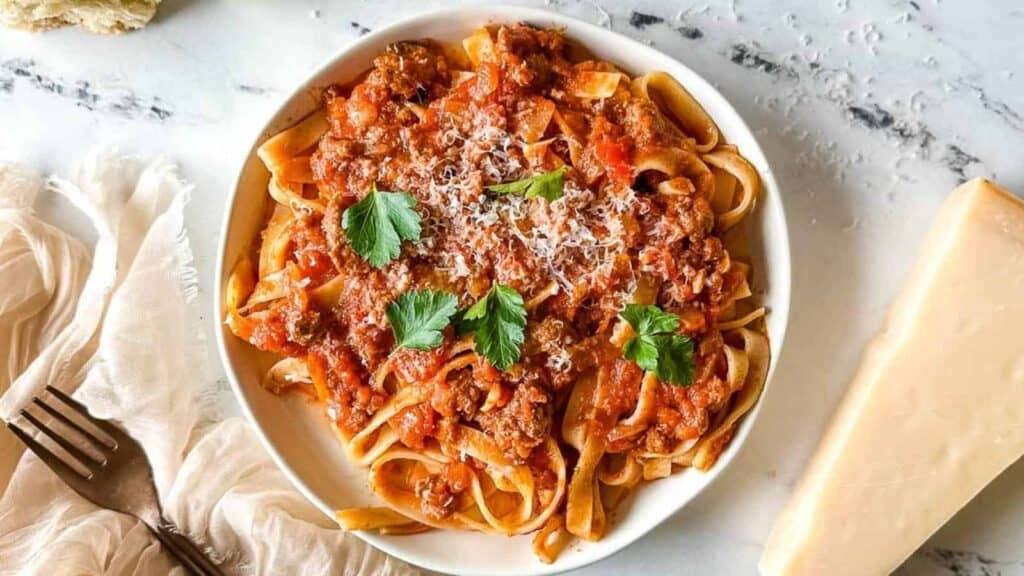 A bowl of spaghetti with meat sauce and parmesan cheese.