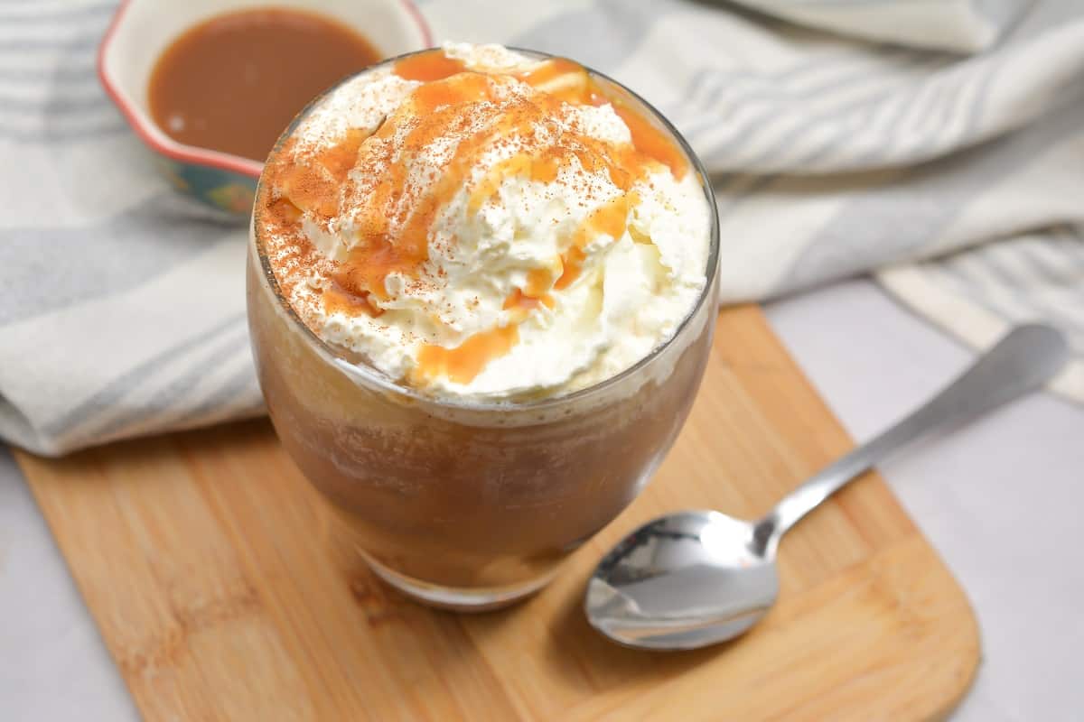 A cup of coffee with caramel and whipped cream.