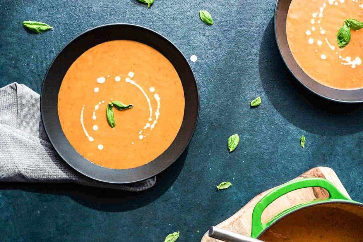 Two bowls of tomato soup on a table with soup recipes