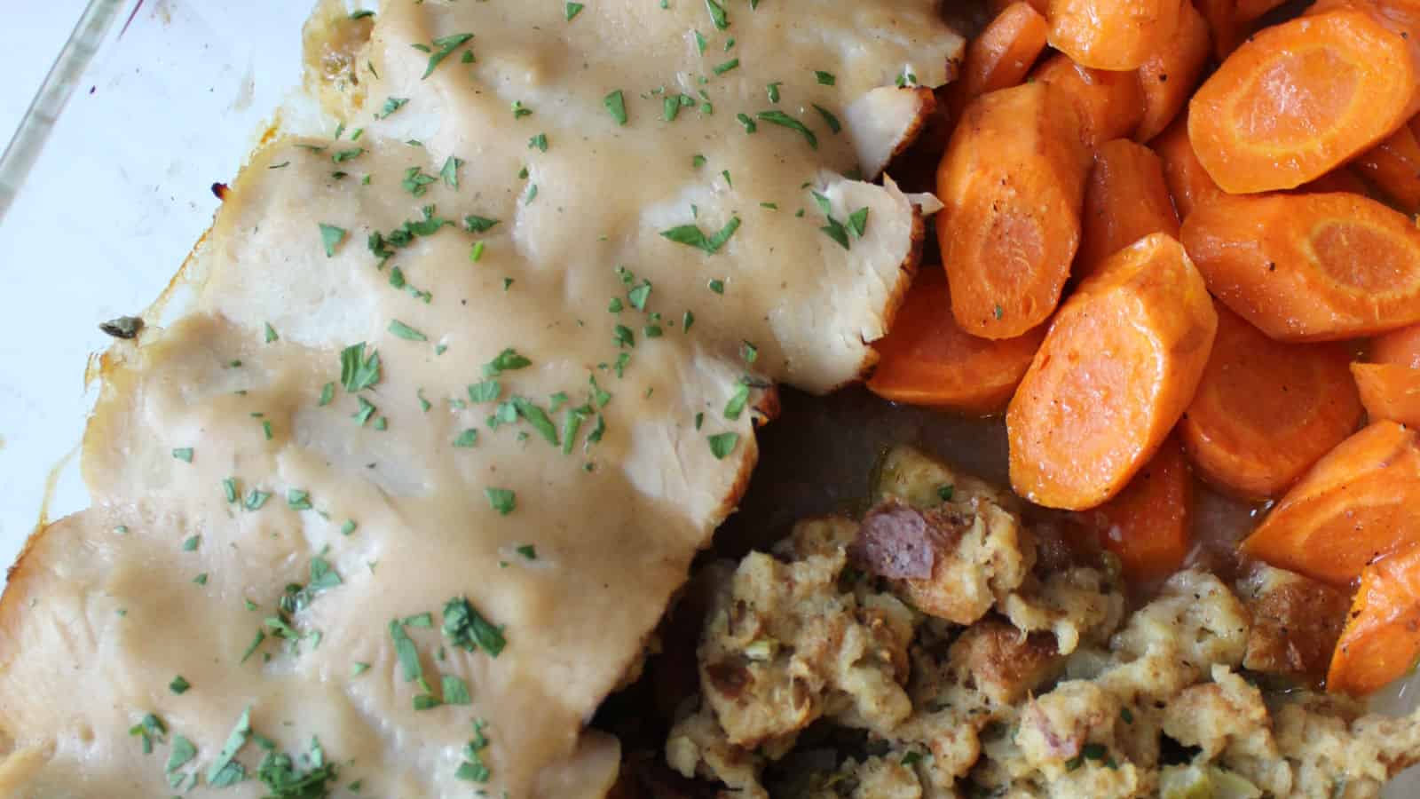 A baking dish with turkey, carrots and stuffing.