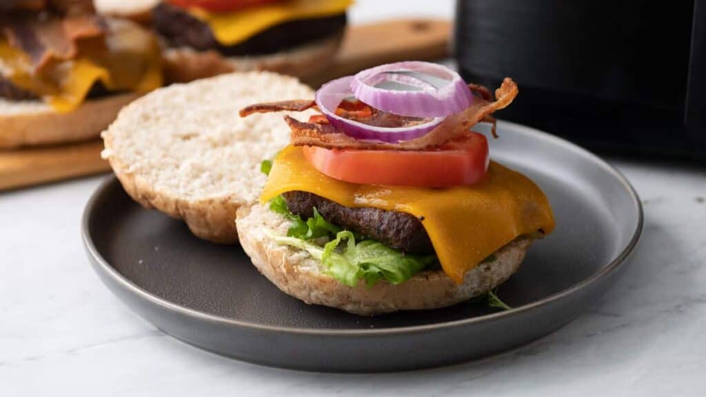 A burger on a plate next to an instant pot.