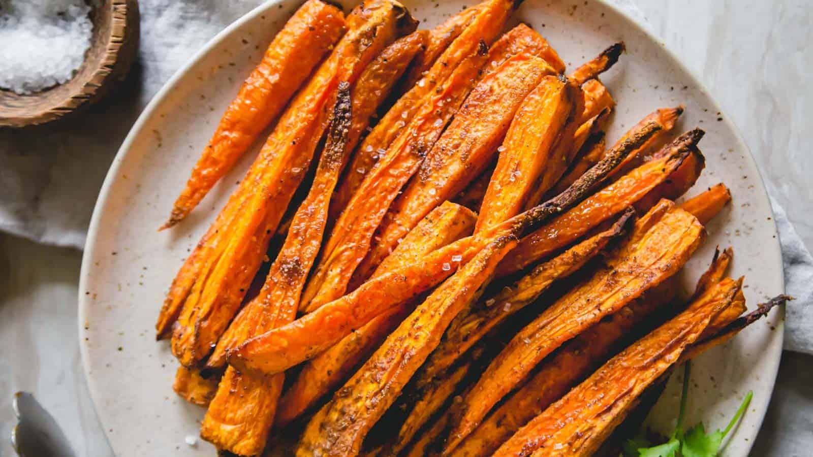 Simply seasoned roasted air fryer carrots on a plate with coarse sea salt garnish.