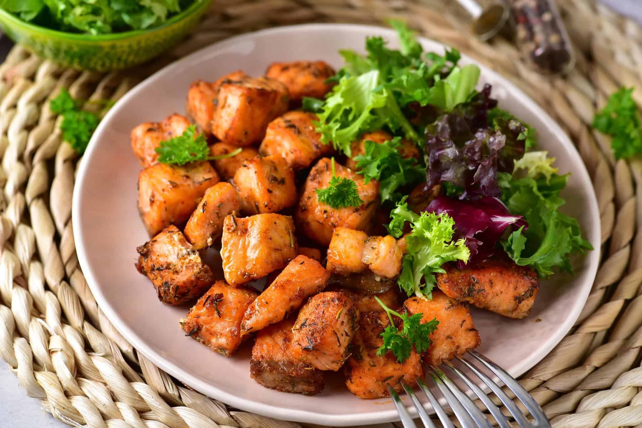 Salmon bites on a plate with a fork.