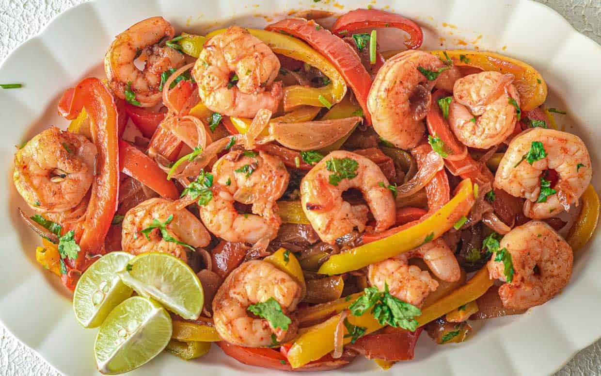 Plate with shrimp, onions, red bell peppers and yellow bell peppers for fajitas.