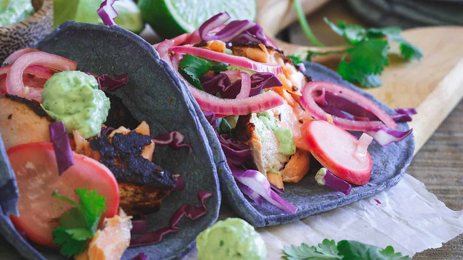 Blackened salmon tacos in blue tortillas.