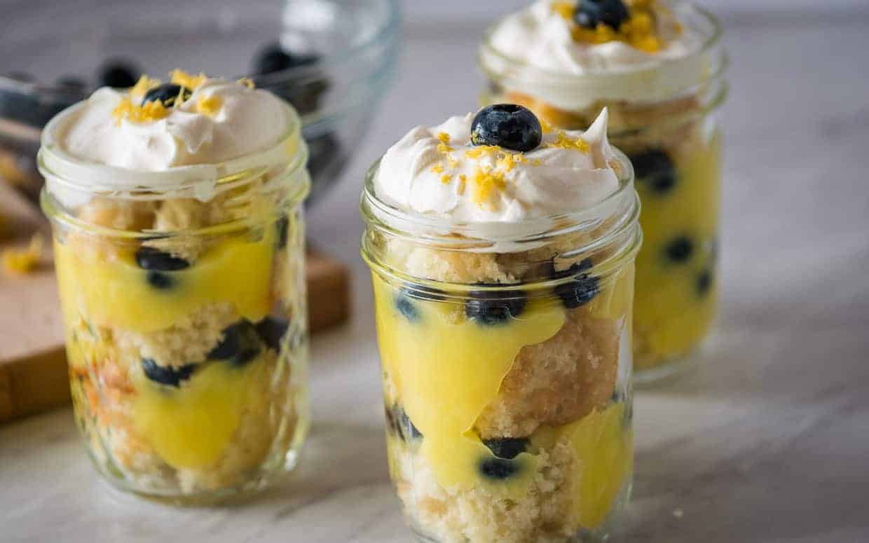 Three mason jars full of blueberry lemon trifle topped with whipped cream.