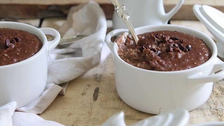 Two white mugs with chocolate oatmeal in them.