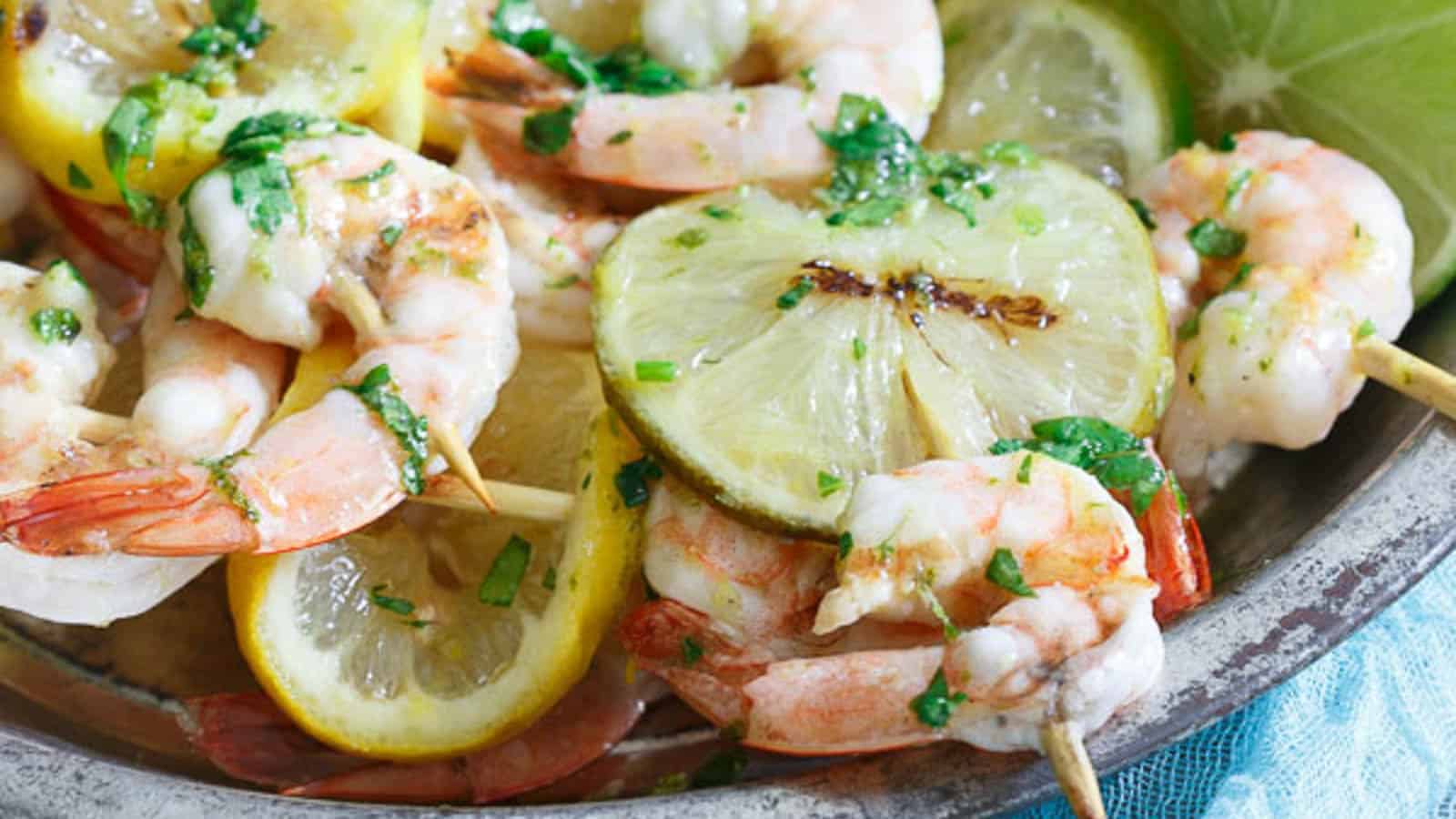 Grilled citrus shrimp skewers with lime slices.