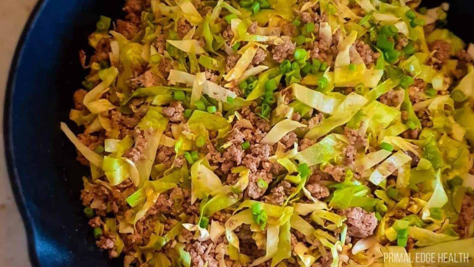 A picture of cabbage stir fry in cast iron skillet.