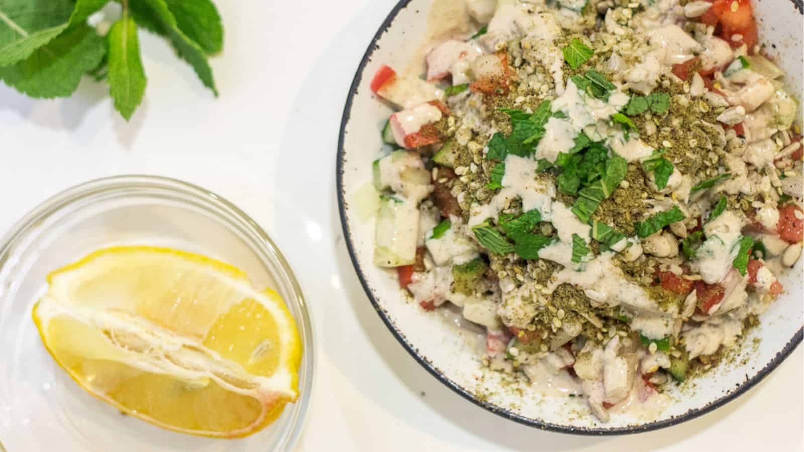 A bowl of salad with a slice of lemon next to it, perfect for preparing quick recipes.