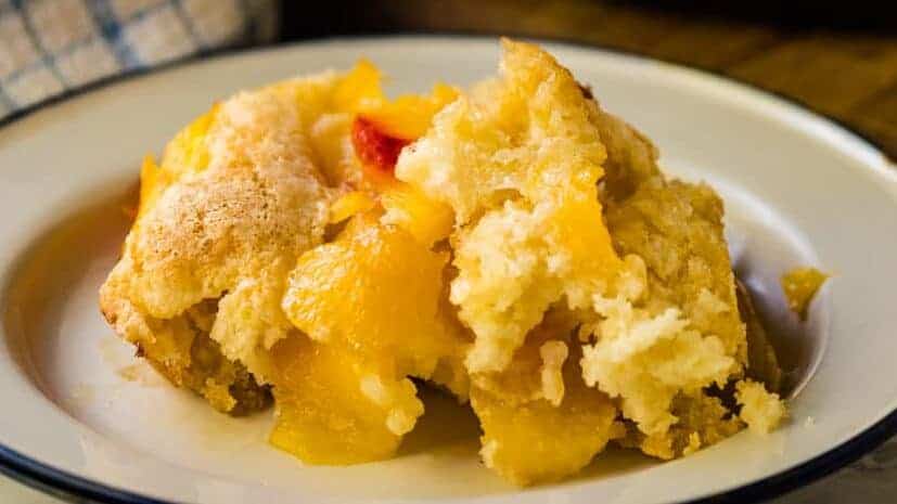 Plate with peach cobbler and a blue napkin.