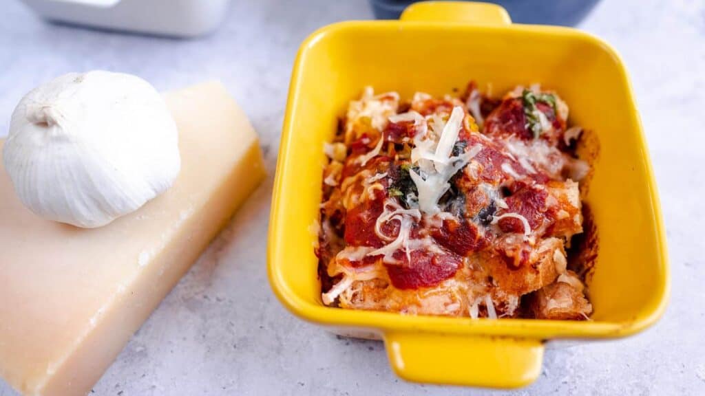 A yellow dish filled with pasta and garlic.