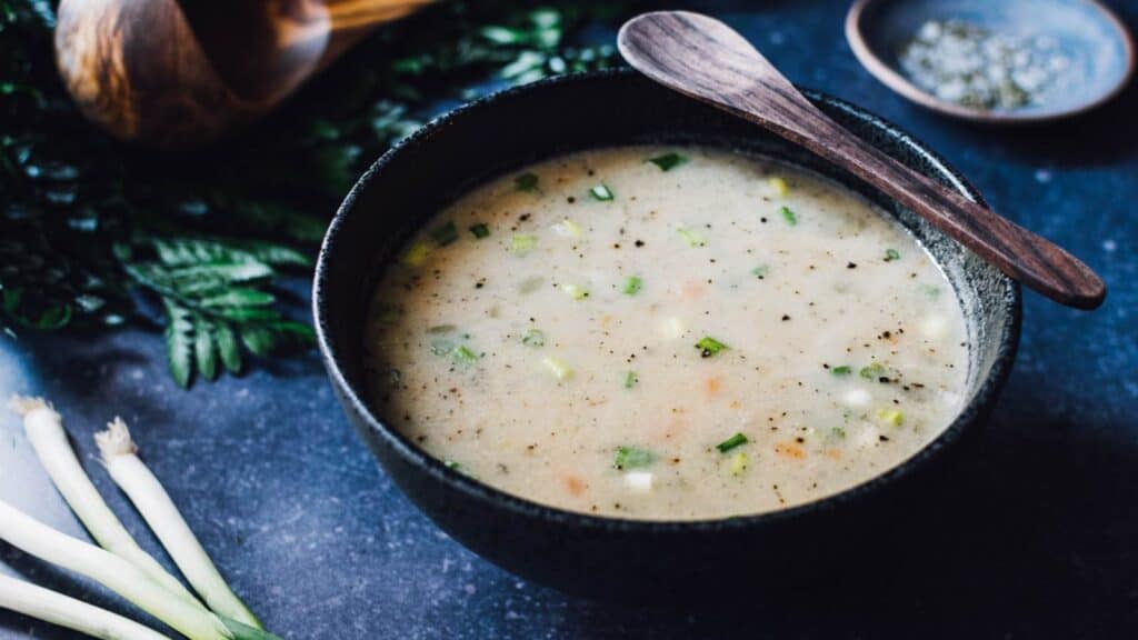 A bowl of soup with vegetables and a spoon.