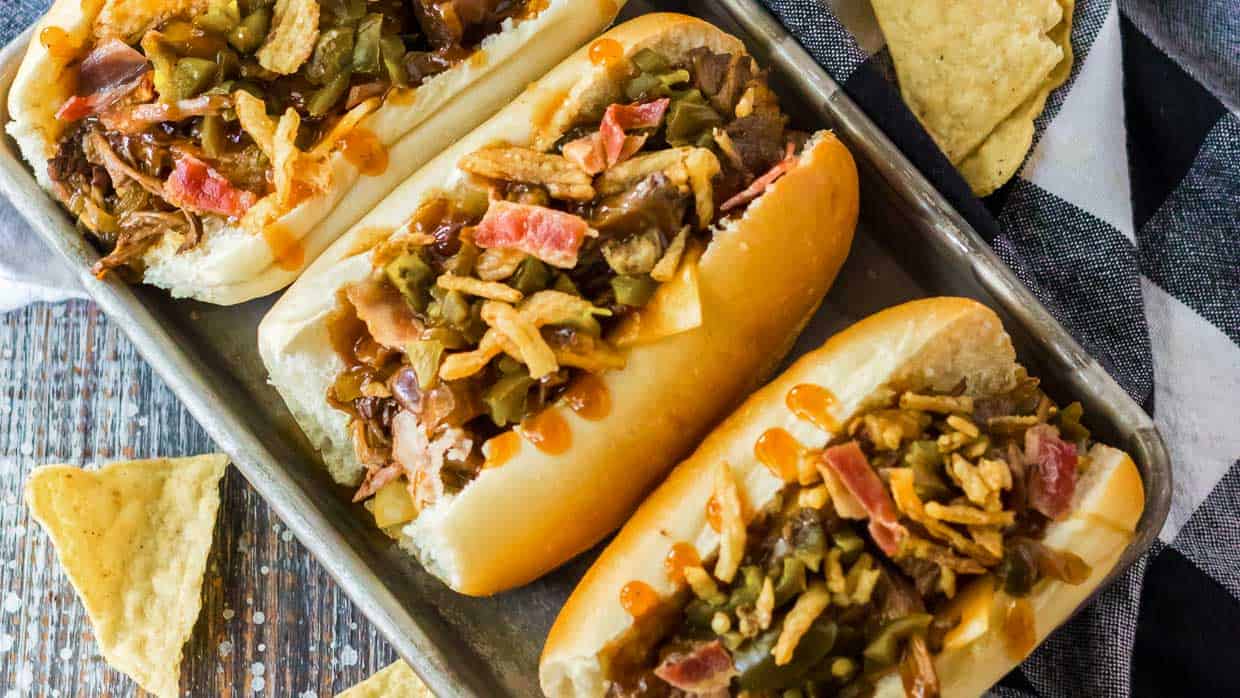 A tray of BBQ beef sandwiches topped with fried onions and bacon.