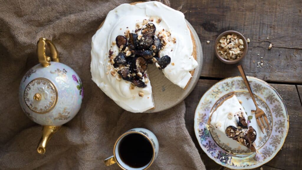 A classic dessert, a pie with a slice missing, is sitting on a table next to a cup of coffee.