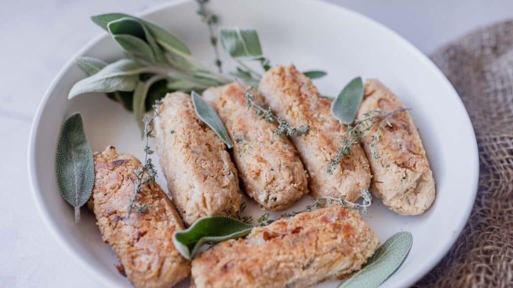 A white plate with bread sticks and sage sprigs.